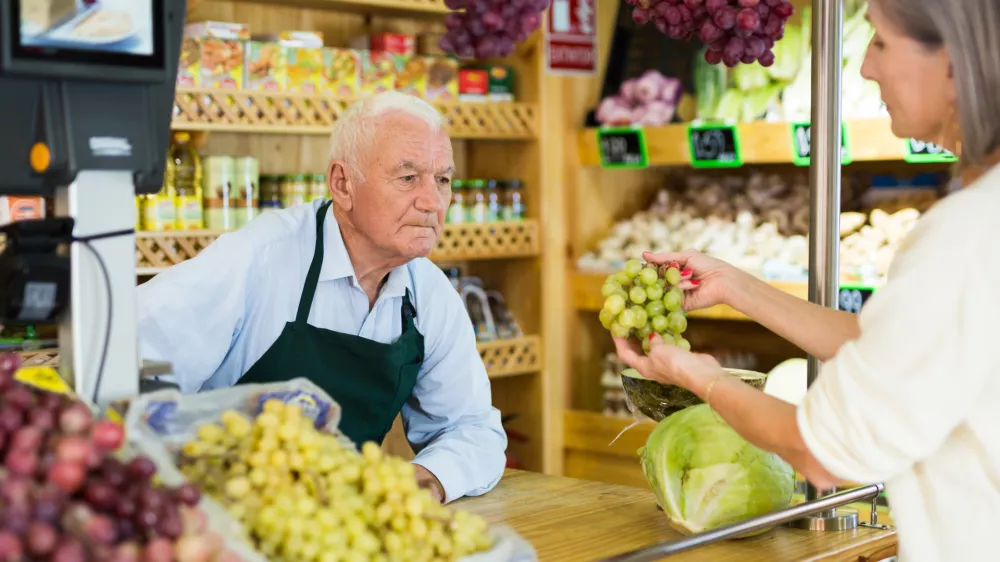 Woman asks the seller to weigh bunch of grapes on the scales / Foto: Jackf