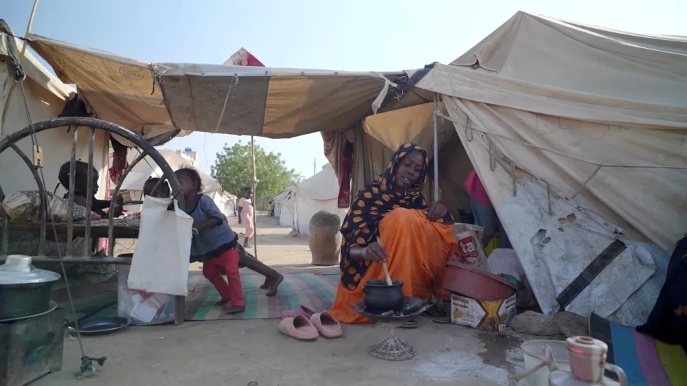 Awadiya Al-Day Ibrahim prepares meal for her family with World Food Programme (WFP) food supplies at a tent, in Kassala, Sudan March 19, 2025, in this screengrab obtained from a video. WFP/Handout via REUTERS THIS IMAGE HAS BEEN SUPPLIED BY A THIRD PARTY