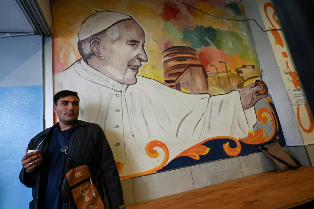 Mož ob papeževi podobi v Buenos Airesu. / Foto: Reuters