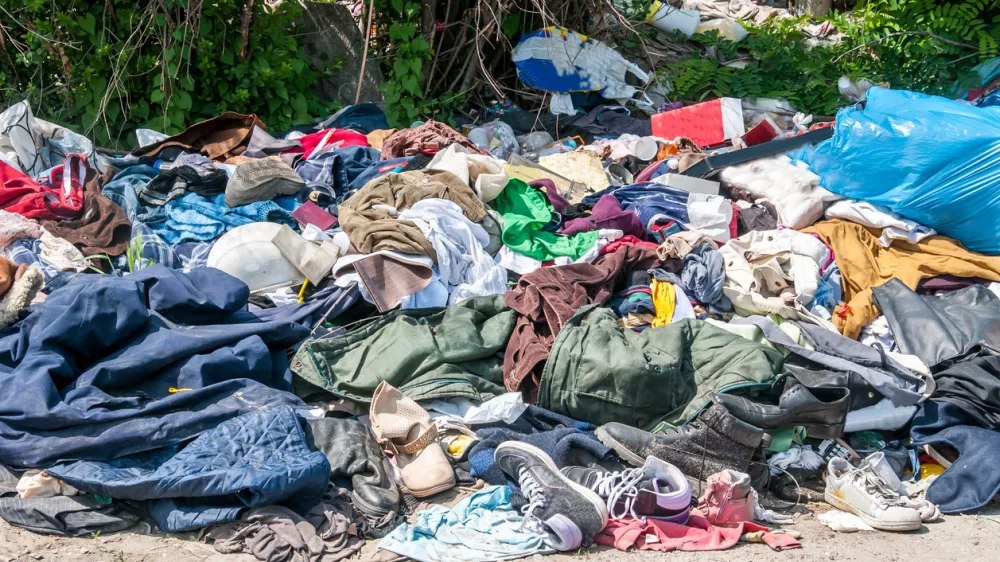 Pile of old clothes and shoes dumped on the grass as junk and garbage, littering and polluting the environment / Foto: Srdjanns74