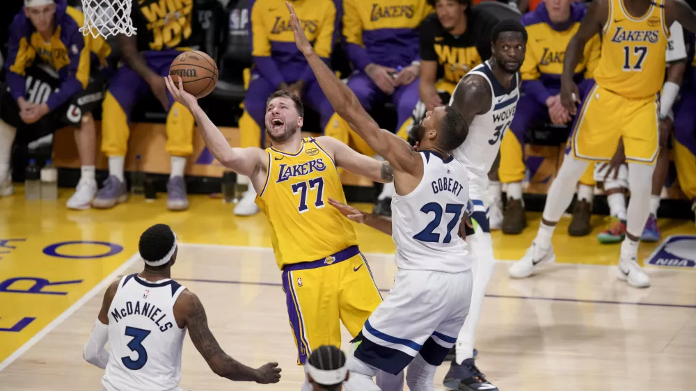 Los Angeles Lakers guard Luka Doncic (77) goes to the basket against Minnesota Timberwolves center Rudy Gobert (27) and forward Jaden McDaniels (3) during the second half of Game 2 of an NBA basketball first-round playoff in Los Angeles, Tuesday, April 22, 2025. (AP Photo/Eric Thayer)