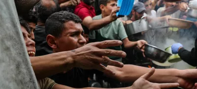Palestinians wait to receive food cooked by a charity kitchen, in Beit Lahia, northern Gaza Strip, April 24, 2025. REUTERS/Mahmoud Issa