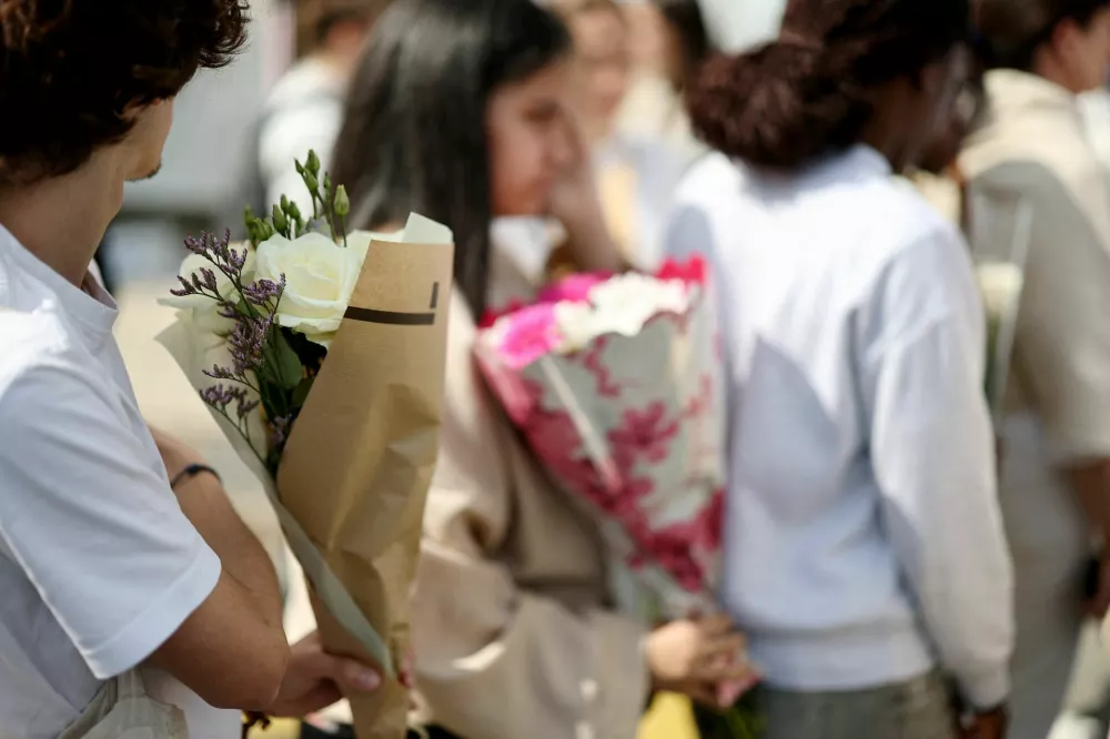 High school students hold flowers as they arrive to attend a tribute gathering at the Notre-Dame-de-Toutes-Aides private school the day after one high school student was killed and three others injured in a stabbing attack by a 15-year-old boy, in Nantes, France, April 25, 2025. REUTERS/Stephane Mahe
