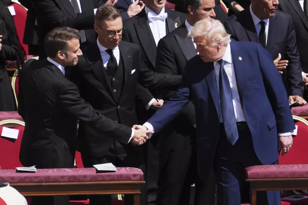 President Donald Trump, right, shakes hands with French President Emmanuel Macron, left, as Finland's President Alexander Stubb, looks on, as they attend the funeral of Pope Francis in St. Peter's Square at the Vatican, Saturday, April 26, 2025. (AP Photo/Evan Vucci)