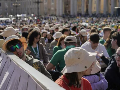 A young man rests as youths gather for a mass presided by Vatican Secretary of State, Cardinal Pietro Parolin, on the second of nine days of mourning for late Pope Francis, in St. Peter's Square, at the Vatican, Sunday, April 27, 2025. (AP Photo/Gregorio Borgia)