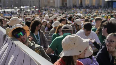 A young man rests as youths gather for a mass presided by Vatican Secretary of State, Cardinal Pietro Parolin, on the second of nine days of mourning for late Pope Francis, in St. Peter's Square, at the Vatican, Sunday, April 27, 2025. (AP Photo/Gregorio Borgia)
