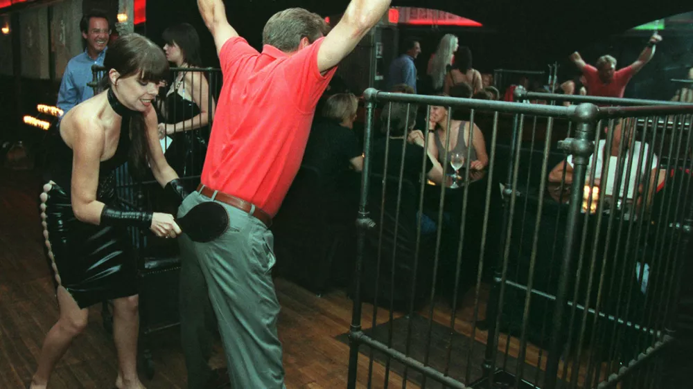 A waitress at La Nouvelle Justine paddles a customer at the S&M restaurant in New York Monday night, Aug. 11, 1997. The customer, who declined to give his name, was treated to the $20 spanking from the "special menu" by friends who took him to the restaurant after his bachelor party earlier in the evening. (AP Photo/Emile Wamsteker)