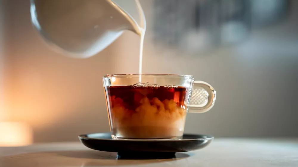 A close-up shot of a poring milk in a hot tea. / Foto: Wirestock