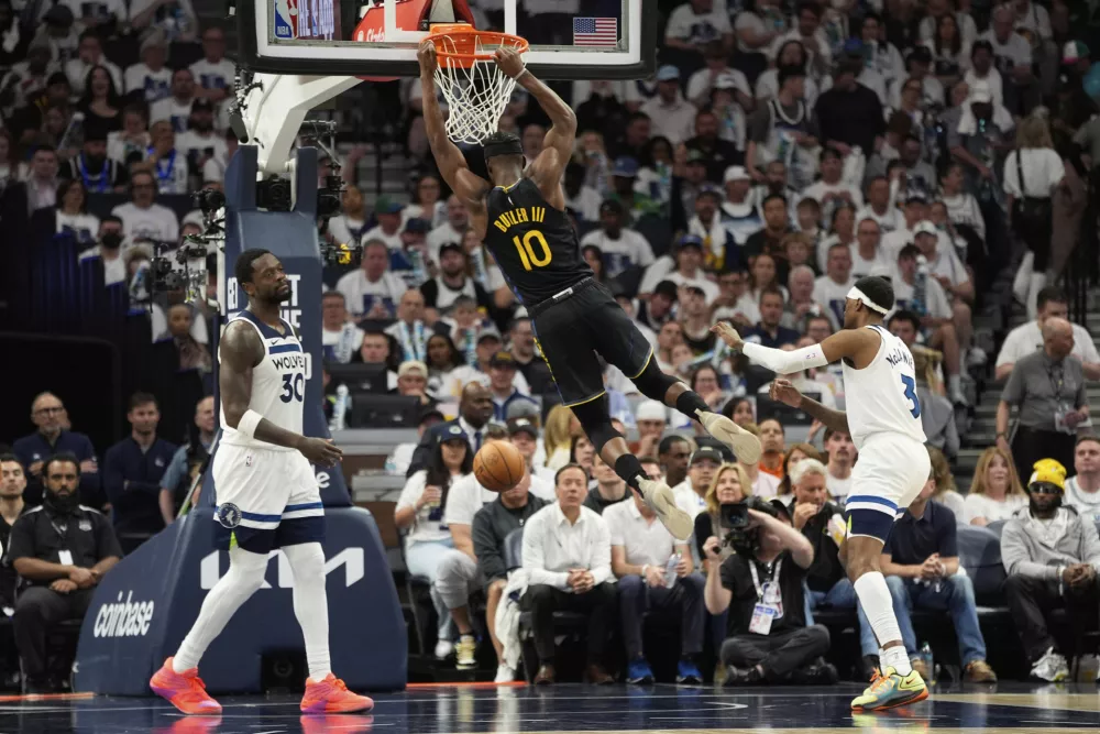 Golden State Warriors forward Jimmy Butler (10) hangs on the rim after a dunk during the second half of Game 1 of an NBA basketball second-round playoff series against the Minnesota Timberwolves, Tuesday, May 6, 2025, in Minneapolis. (AP Photo/Abbie Parr)