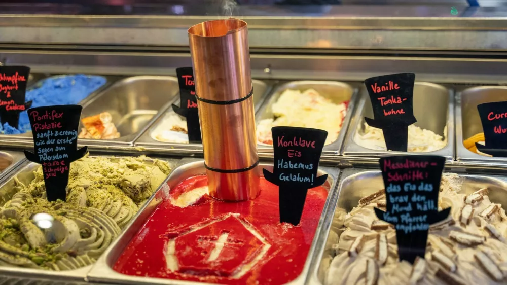 07 May 2025, Bavaria, Munich: In the Munich ice cream parlor "Der verr&uuml;ckte Eismacher - im Wunderland", the ice cream counter features the "Conclave ice cream" variety with a small chimney with incense and a tiara, the well-known papal headdress, painted into the ice cream. Photo: Leonie Asendorpf/dpa,Image: 996185861, License: Rights-managed, Restrictions: GERMANY OUT, Model Release: no