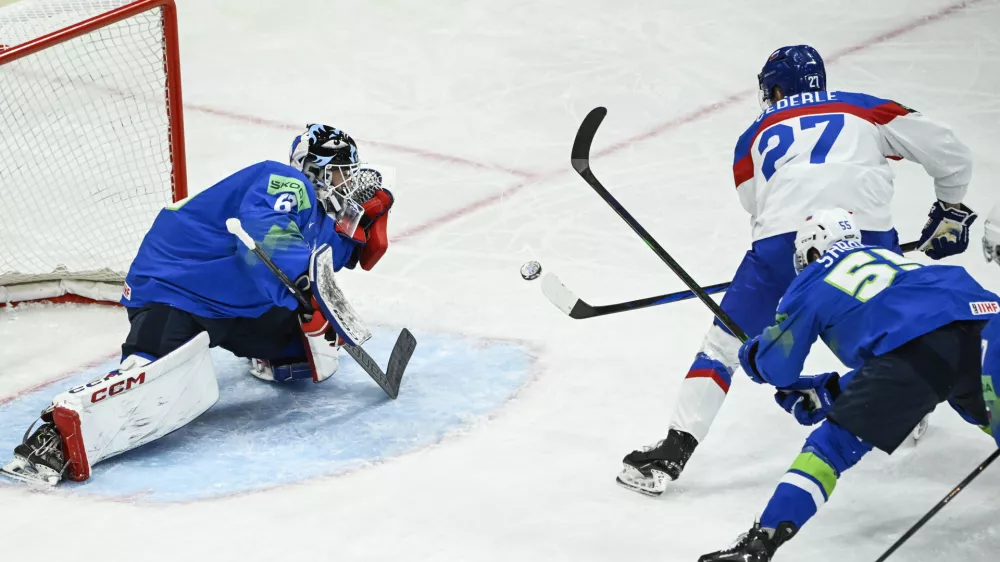 Slovakia's Sebastian Cederle (27) scores the opening goal at Slovenia's goalkeeper Matija Pintaric, left, during a Group A match between Slovakia and Slovenia at the hockey world championships at Avicii Arena in Stockholm, Sweden Sunday, May 11, 2025. (Fredrik Sandberg/TT News Agency via AP)