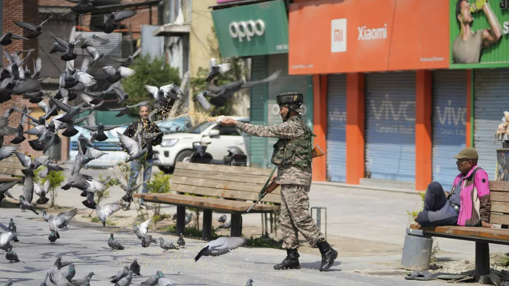 An Indian soldier feeds pigeons at a market, day after India and Pakistan agreed to a ceasefire Saturday following U.S.-led talks to end the most serious military confrontation between the nuclear-armed rivals in decades, in Srinagar, in Indian controlled Kashmir, Sunday, May 11, 2025.(AP Photo/Mukhtar Khan)