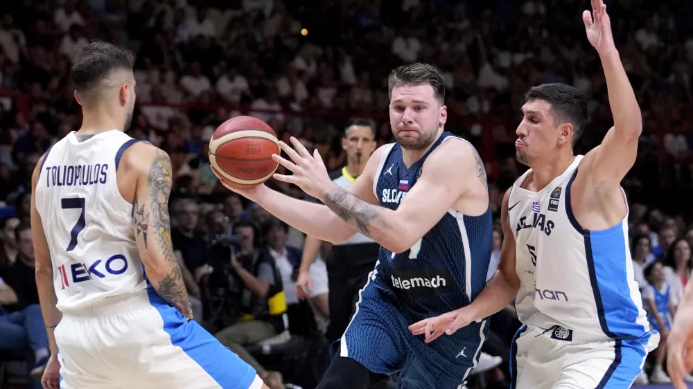 Slovenia's Luka Doncic drives between Greece's Giannoulis Larentzakis, right, and Vasileios Toliopoulos during an Acropolis tournament basketball match, at the Peace and Friendship indoor stadium at Athens' port city of Piraeus, Greece, Saturday, July 6, 2024. (AP Photo/Petros Giannakouris)