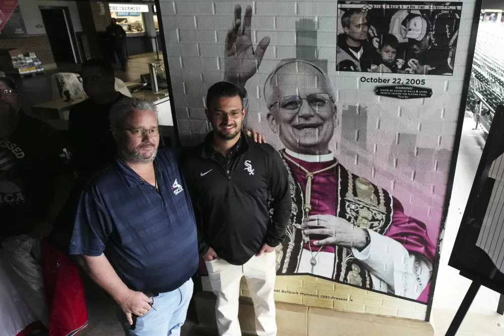 Eddie Schmit III, left, and his son Eddie Schmit IV, right, pose for a photo after a news conference for the Chicago White Sox's commemoration of team fan Pope Leo XIV with a graphic installation at Rate Field before a baseball game between the Seattle Mariners and the White Sox in Chicago, Monday, May 19, 2025. (AP Photo/Nam Y. Huh) / Foto: Nam Y. Huh