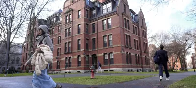 FILE - People walk between buildings, Dec. 17, 2024, on the campus of Harvard University in Cambridge, Mass. (AP Photo/Steven Senne, File)