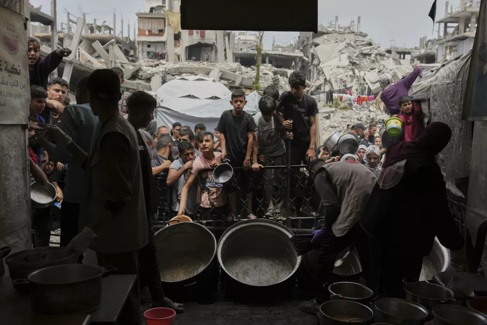 Palestinians struggle to get donated food at a community kitchen in Jabalia, northern Gaza Strip, Thursday, May 15, 2025. (AP Photo/Jehad Alshrafi)