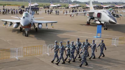 Chinese Air Force personnel march past the Chinese military's J10C fighter and JH-7A2 fighter bomber during 13th China International Aviation and Aerospace Exhibition, also known as Airshow China 2021, Wednesday, Sept. 29, 2021, in Zhuhai in southern China's Guangdong province. With record numbers of military flights near Taiwan over the last week, China has been stepping up its harassment of the island it claims as its own, showing an new intensity and sophistication as it asserts its territorial claims in the region. (AP Photo/Ng Han Guan)