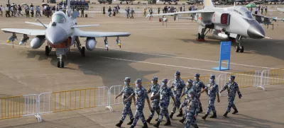 Chinese Air Force personnel march past the Chinese military's J10C fighter and JH-7A2 fighter bomber during 13th China International Aviation and Aerospace Exhibition, also known as Airshow China 2021, Wednesday, Sept. 29, 2021, in Zhuhai in southern China's Guangdong province. With record numbers of military flights near Taiwan over the last week, China has been stepping up its harassment of the island it claims as its own, showing an new intensity and sophistication as it asserts its territorial claims in the region. (AP Photo/Ng Han Guan)