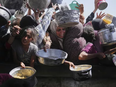 Palestinians struggle to get donated food at a community kitchen in Khan Younis, Gaza Strip, Friday, May 16, 2025. (AP Photo/Abdel Kareem Hana)