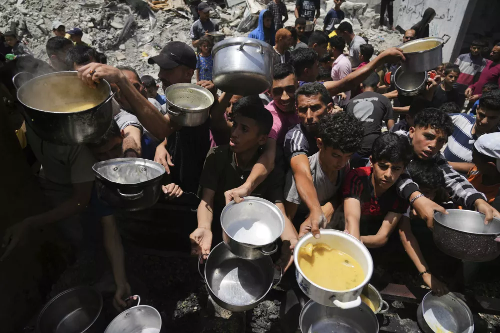 Palestinians struggle to get donated food at a community kitchen in Jabalia, northern Gaza Strip, Monday, May 19, 2025. (AP Photo/Jehad Alshrafi)