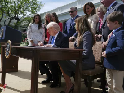 President Donald Trump signs a bill for the "Take it Down Act" as first lady Melania Trump, seated right, Rep. Maria Salazar R-Fla., standing from fourth right, Sen. Ted Cruz, R-Texas, background center, and others watch as Trump in the Rose Garden of the White House, Monday, May 19, 2025, in Washington. (AP Photo/Evan Vucci)