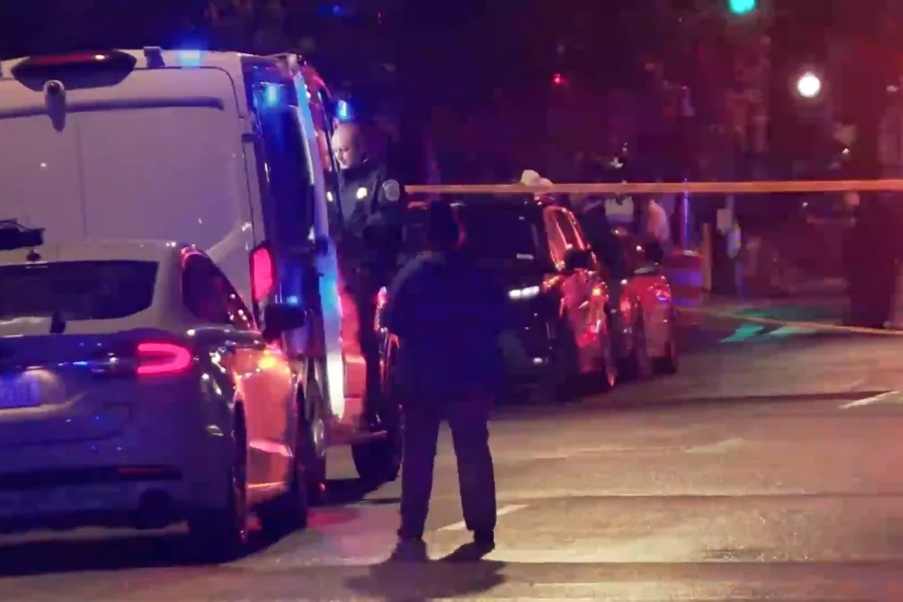In this image taken from video provided by WJLA, a spectator watches as law enforcement works the scene after two staff members of the Israeli embassy in Washington were shot and killed&nbsp;outside the Capital Jewish Museum on Wednesday, May 21, 2025, in Washington. (WJLA via AP)