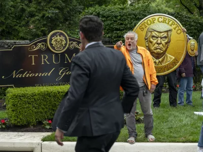 IMAGE DISTRIBUTED FOR OUR REVOLUTION - An activist calls out an attendee of an exclusive dinner at Trump National Golf Course as he and fellow activist from Our Revolution protest influence-peddling & corruption, Thursday, May 22, 2025 in Sterling, Va. Inside, the top 220 holders of the President's cryptocurrency have paid over 4 million for spots at an exclusive dinner with Trump. (Kevin Wolf/AP Content Services for Our Revolution)