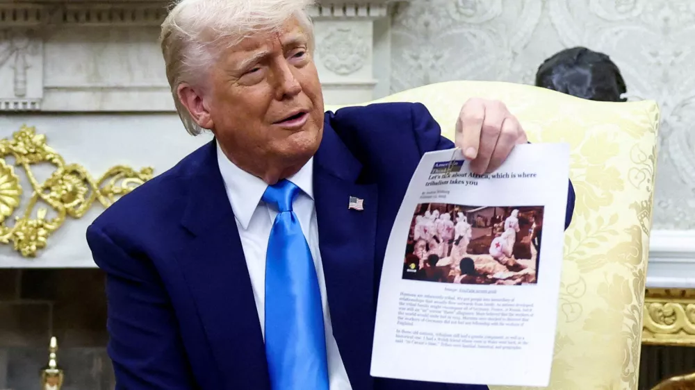 FILE PHOTO: U.S. President Donald Trump shows a copy of an article that he said is about white South Africans who had been killed, in the Oval Office of the White House in Washington, D.C., U.S., May 21, 2025. REUTERS/Kevin Lamarque/File Photo