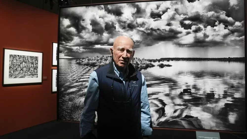 FILE - Brazilian photographer Sebastiao Salgado poses in front of one of the pictures of his 'Amazonia' exhibition in Milan, Italy, May 11, 2023. Salgado, known for his long-term projects and images of nature and humanity, died at age 81, the Instituto Terra confirmed on Friday, May 23, 2025.. (AP Photo/Luca Bruno, File)