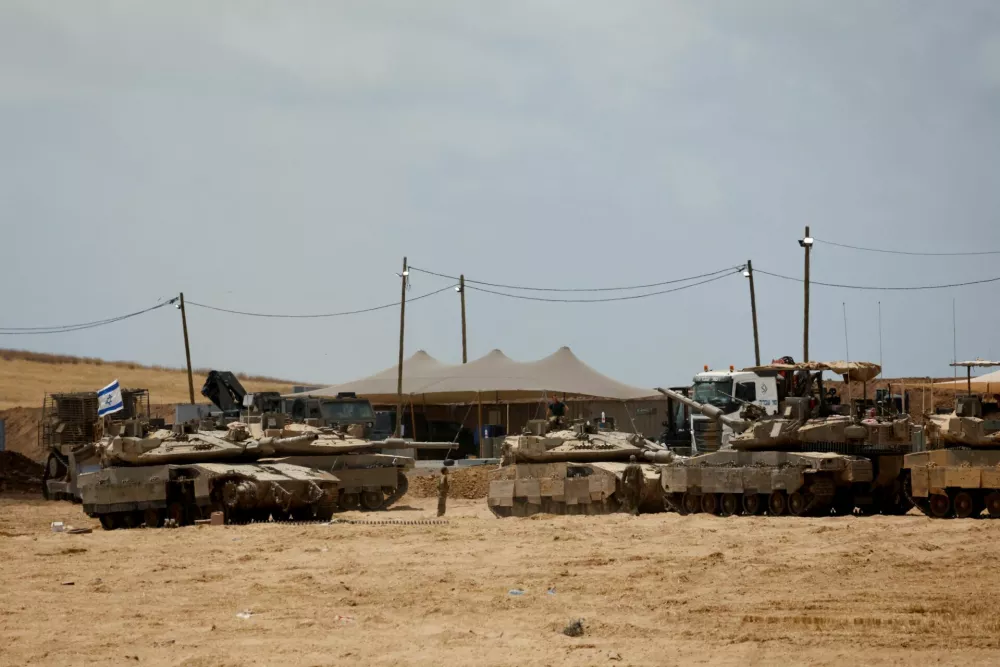 Israeli soldiers stand next to military vehicles near the Israel-Gaza border, as seen from Israel, May 22, 2025. REUTERS/Ammar Awad