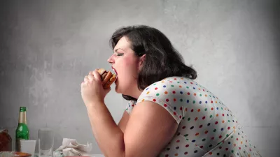 Fat woman sitting at table and eating a hamburger / Foto: Bowie15
