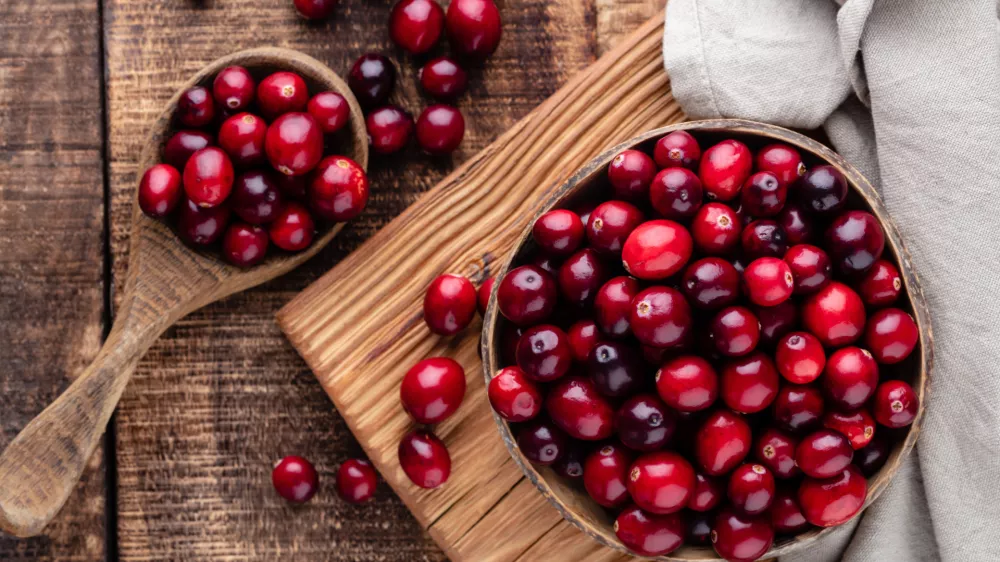 Ripe cranberry in wooden bowl on wooden table. / Foto: Gitusik