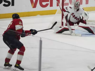Florida Panthers defenseman Niko Mikkola, left, shoots to score a goal against Carolina Hurricanes goaltender Pyotr Kochetkov, right, during the third period in Game 3 of the NHL hockey Stanley Cup Eastern Conference finals Saturday, May 24, 2025, in Sunrise, Fla. (AP Photo/Lynne Sladky)