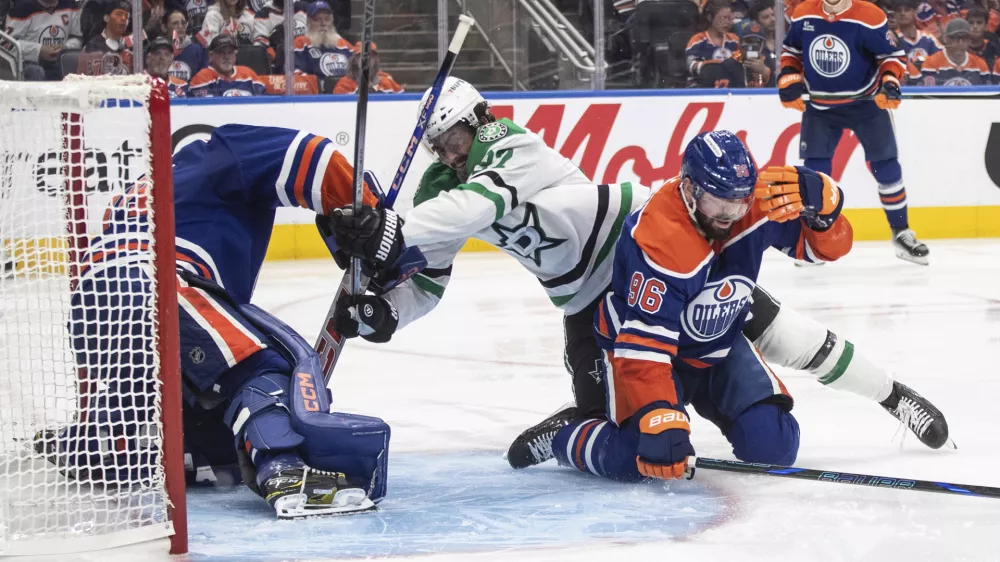 Dallas Stars' Mason Marchment (27) and Edmonton Oilers' Jake Walman (96) battle as Oilers goalie Stuart Skinner, left, makes a save during the third period of Game 3 of the NHL hockey Stanley Cup Western Conference finals in Edmonton, Alberta, Sunday, May 25, 2025. (Jason Franson/The Canadian Press via AP)