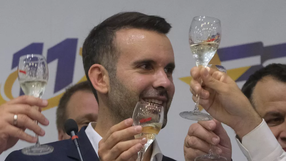 Milojko Spajic, president of the centrist Europe Now party raises a glass of champagne at his headquarters after parliamentary election in Montenegro's capital Podgorica, Sunday, June 11, 2023. A recently formed centrist group that advocates Montenegro joining the European Union was projected to win the small Balkan country's early parliamentary election Sunday, but without enough support to form a government on its own, according to independent vote monitors. (AP Photo/Risto Bozovic)