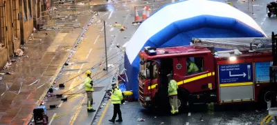 Police and emergency personnel walk next to a tent at the site of an incident on Water Street near the Liver Building in Liverpool after a car collided with pedestrians during the Premier League winners parade, in Liverpool, England, Monday May 26, 2025. (Danny Lawson/PA via AP)