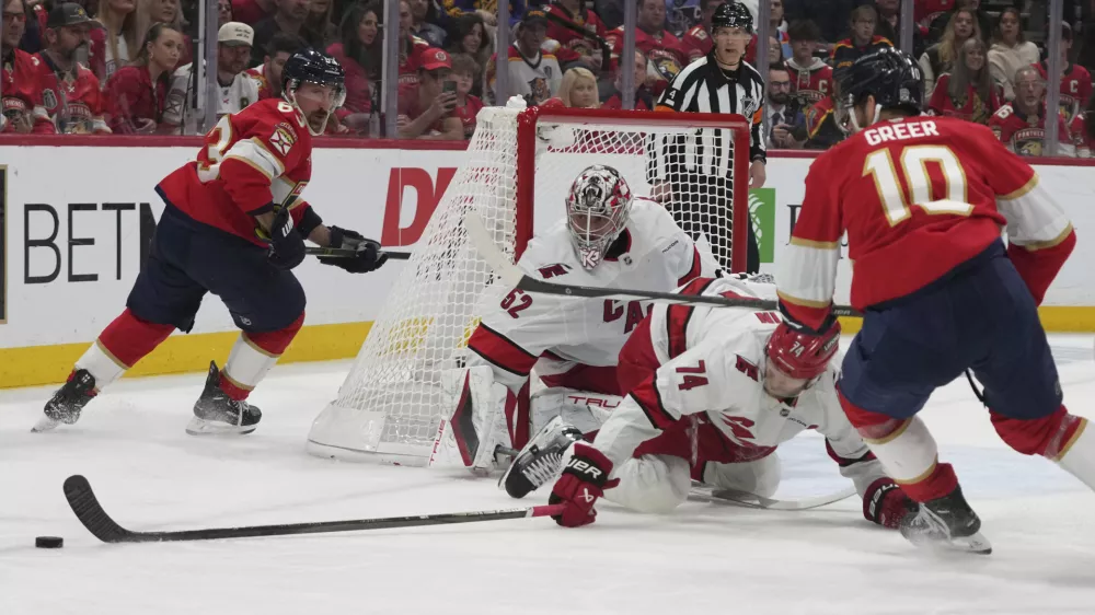 Carolina Hurricanes defenseman Jaccob Slavin (74) goes for the puck against Florida Panthers left wing A.J. Greer (10) during the second period in Game 3 of the NHL hockey Stanley Cup Eastern Conference finals Saturday, May 24, 2025, in Sunrise, Fla. (AP Photo/Lynne Sladky)