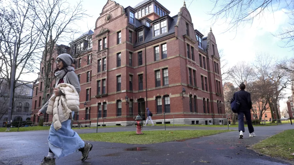 FILE - People walk between buildings, Dec. 17, 2024, on the campus of Harvard University in Cambridge, Mass. (AP Photo/Steven Senne, File)