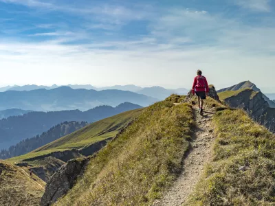 nice senior woman, hiking in fall, autumn on the ridge of the Nagelfluh chain near Oberstaufen, Allgaeu Area, Bavaria, Germany, Hochgrats summit in the background