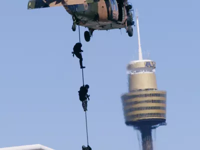 Commandos repel down a rope from one of two Black Hawk helicopters with Sydney's landmark building Center Point Tower behind during a counter terrorism exercise in Sydney, Australia, Sunday, Sept. 28, 2003. The Australian Defense Force held its biggest counter-terrorism exercise since the Sydney Olympics. The demonstration is a test of strength and a show of force prior to next week's Rugby World Cup kick-off. (AP Photo/Mark Baker)
