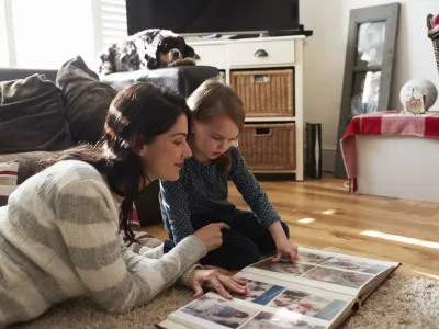 Mother And Daughter At Home Looking Through Photo Album