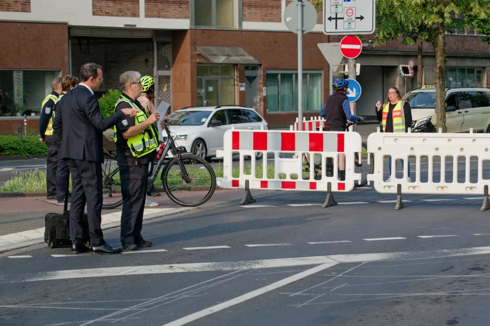 04 June 2025, North Rhine-Westphalia, Cologne: Employees of the public order office explain the road closures due to a bomb disposal operation to passers-by. Three bombs from the Second World War were discovered in the Deutz district on Monday Photo: Henning Kaiser/dpa