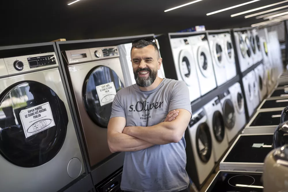 Mirnes Fatic, one of the owners of "Only fools and horses ltd." home appliance store, smiles during an interview for the Associated Press in Hadzici, suburb of Sarajevo, Bosnia, Wednesday, June 4, 2025. (AP Photo/Armin Durgut)