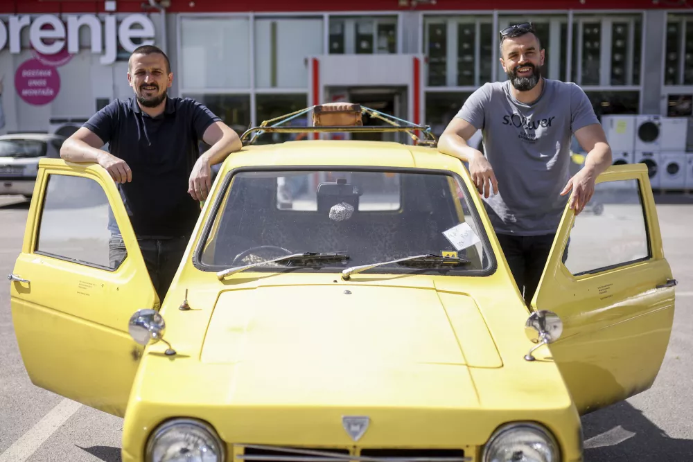 Tarik Fatic, left, and his brother Mirnes pose for a photo next to the Reliant Regal, an exact copy of the famous BBC TV show &nbsp;"Only Fools and Horses" iconic yellow car in Hadzici, suburb of Sarajevo, Bosnia, Wednesday, June 4, 2025. (AP Photo/Armin Durgut)