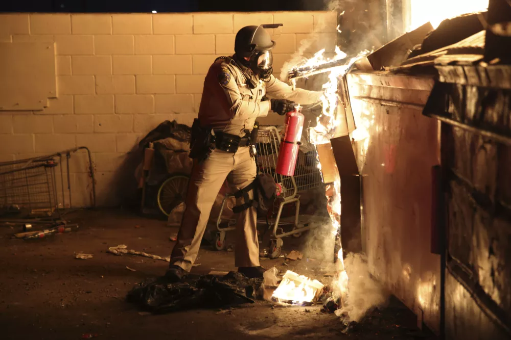 A law enforcement officer works to put out a fire during a protest in Compton, Calif., Saturday, June 7, 2025, after federal immigration authorities conducted operations. (AP Photo/Ethan Swope) / Foto: Ethan Swope