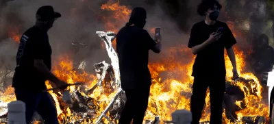08 June 2025, US, Los AngelesProtesters walk by one of several Waymo cars that were set on fire in Downtown LA where hundreds gathered to protest immigration sweeps. PhotoJill Connelly/ZUMA Press Wire/dpa