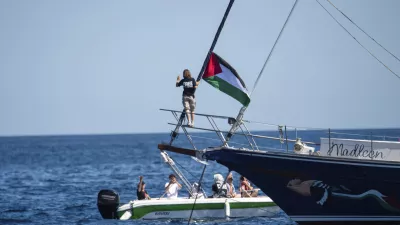 Climate activist Greta Thunberg stands near a Palestinian flag after boarding the Madleen boat and before setting sail for Gaza along with activists of the Freedom Flotilla Coalition, departing from the Sicilian port of Catania, Italy, Sunday, June 1, 2025. (AP Photo/Salvatore Cavalli)
