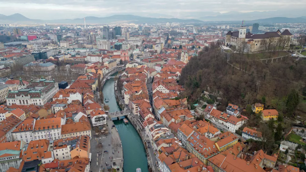 Panorama of Ljubljana city. Aerial view above Ljubljanica river with river cruise boats towards city center. Historical town with old architecture and the castle on the hill. Cloudy day in the winter. / Foto: Izvir8
