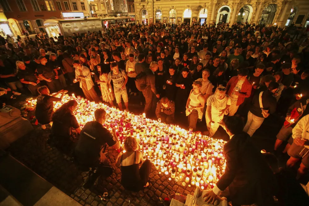People light candles on the main square in the city center after a deadly shooting at a school in Graz, Austria, Tuesday, June 10, 2025. (AP Photo/Heinz-Peter Bader)