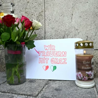 11 June 2025, Austria, Vienna: Candles and flowers are placed in front of St. Stephen's Cathedral in central Vienna, where a poster reads "We mourn with Graz," after a school rampage in Graz left eleven people dead. Photo: Helmut Fohringer/APA/dpa